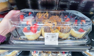 hand holding a package of 8 decorated variety mini cheesecakes