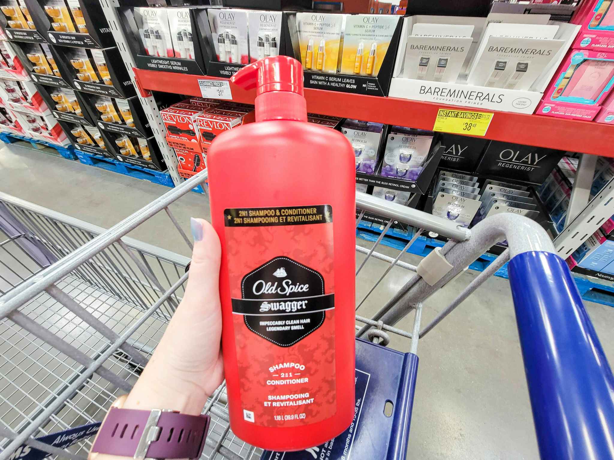 hand holding a large bottle of old spice swagger shampoo and conditioner over a cart