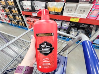 hand holding a large bottle of old spice swagger shampoo and conditioner over a cart