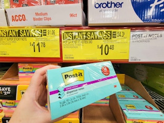 hand holding a pack of multi colored post it notes