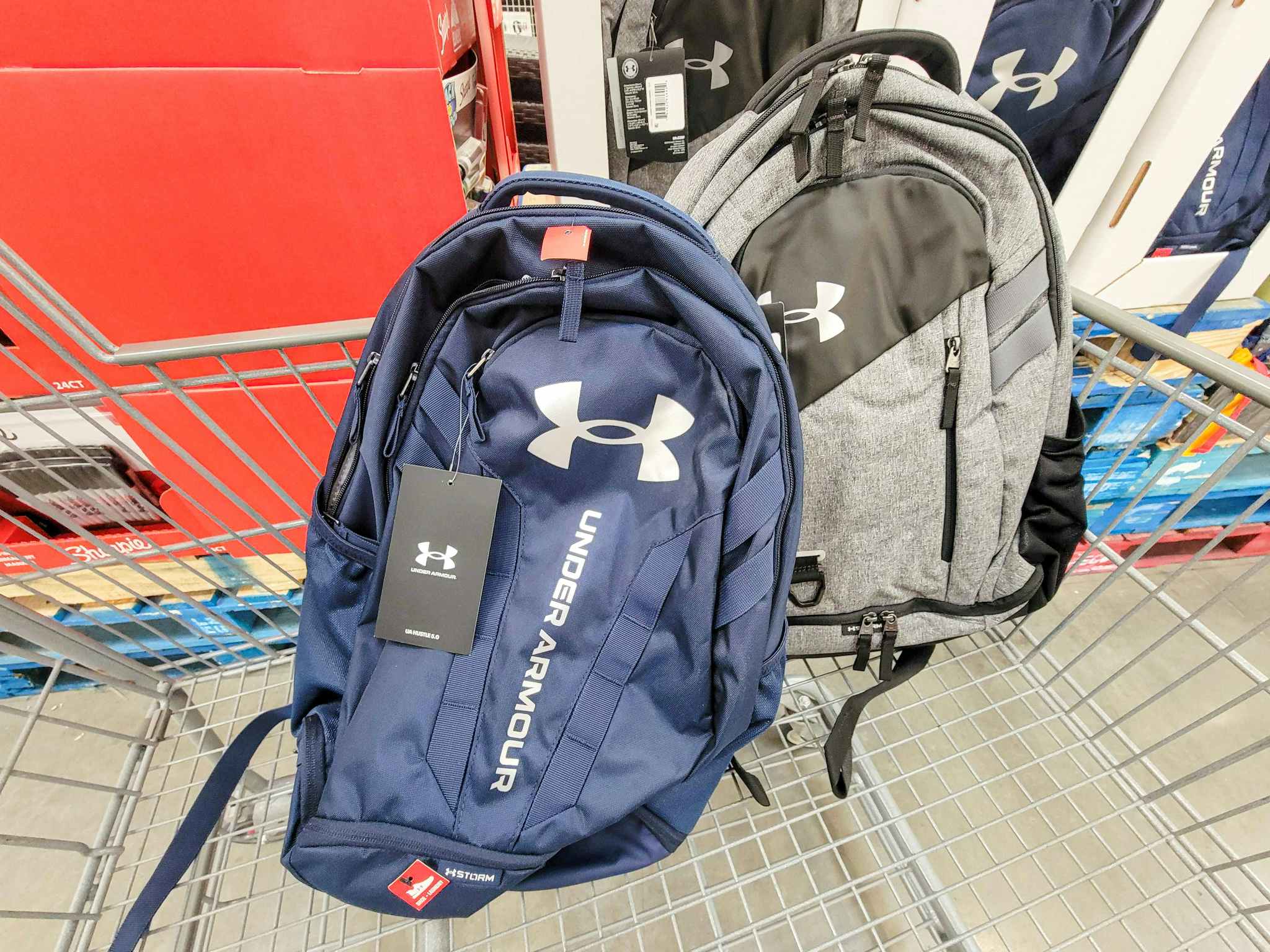 2 under armour backpacks in a cart, one blue and one grey