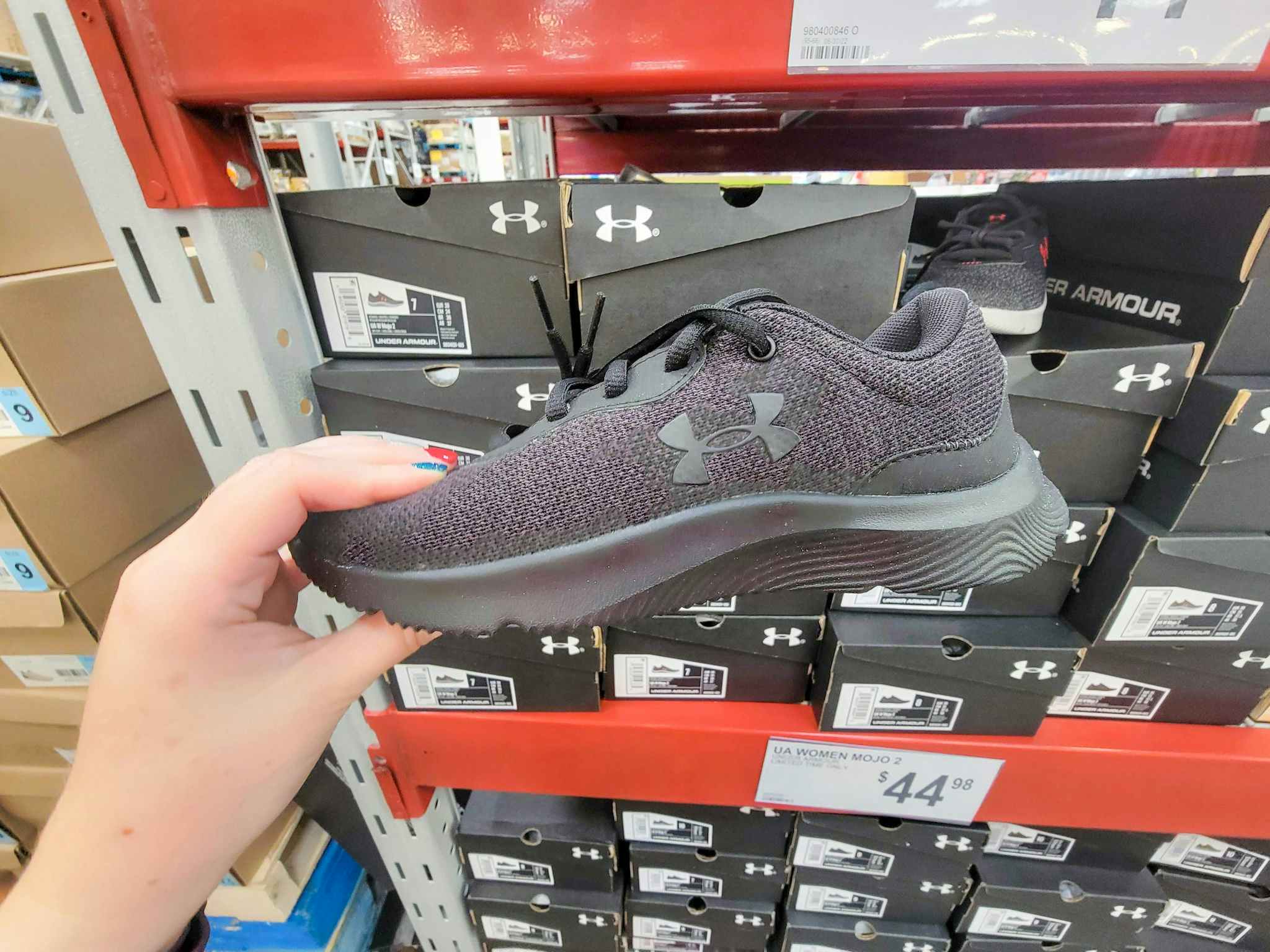 hand holding a black under armour running shoe
