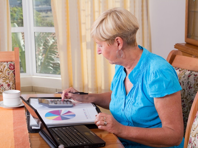 Senior woman sitting at a desk calculating personal budget and Social Security increase