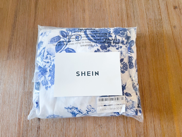 a blue and white dress from SheIn packaged in a bag with the SheIn logo on top of it