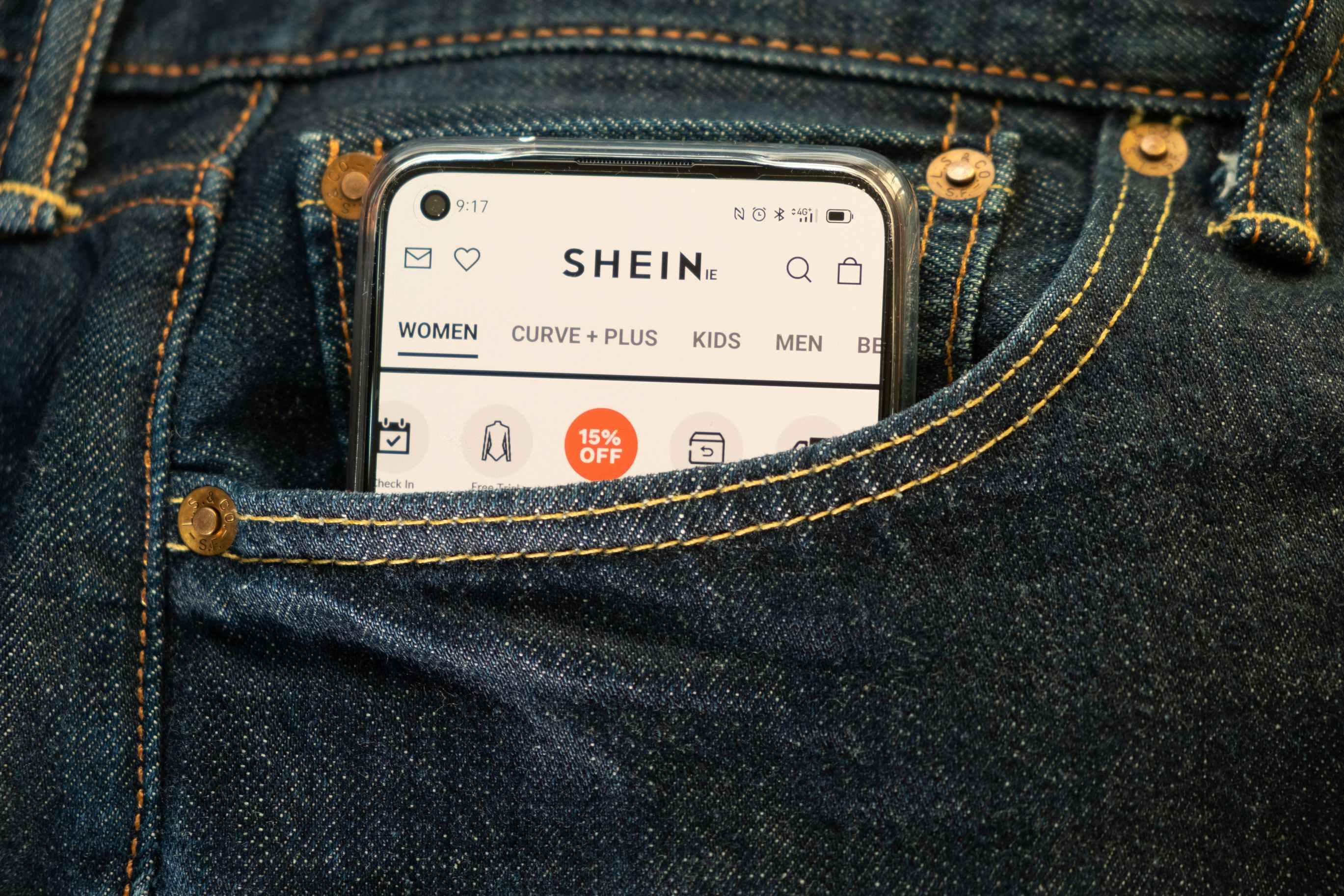 the shein app open on an iphone that's tucked into the pocket of denim jeans