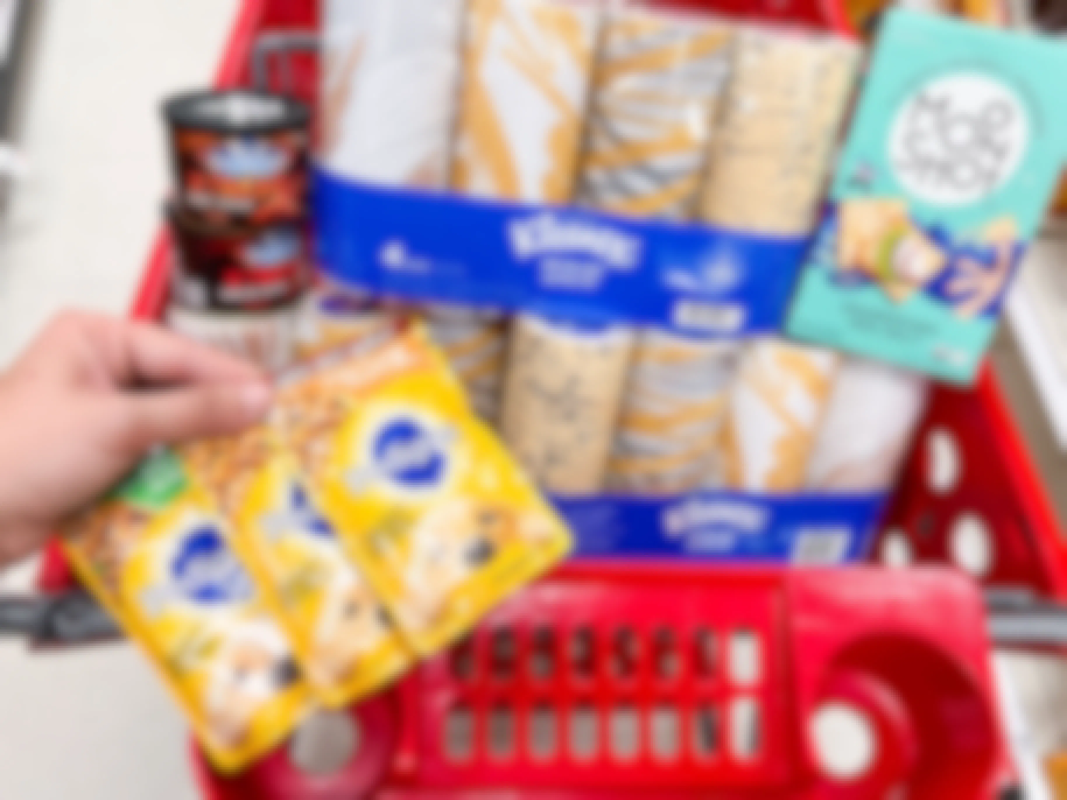 A target shopping cart containing kleenex 4 packs, a box of moonshot crackers, pedigree dog food packs, and blue diamond almond extremes