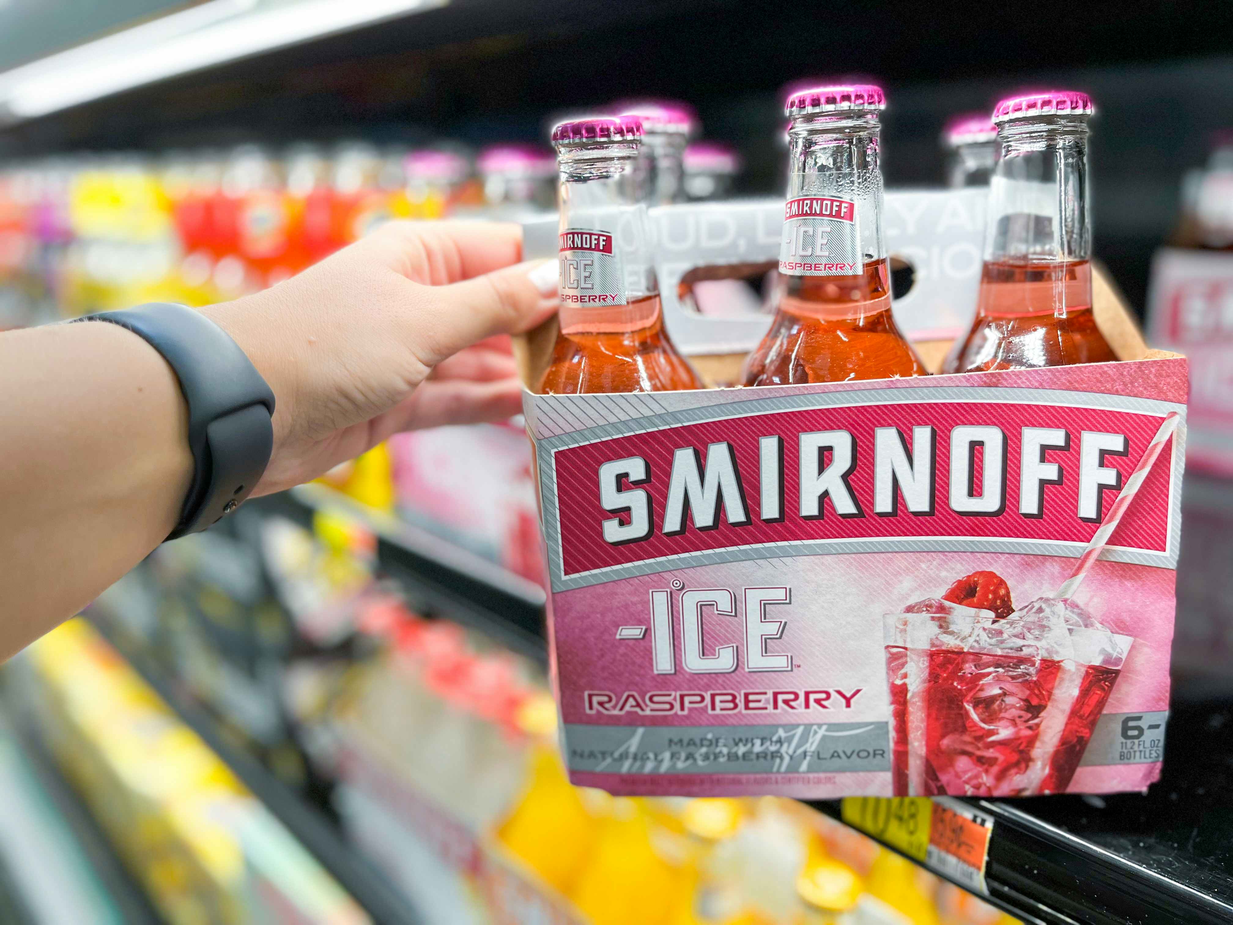 hand reaching for angled 6-pack of Smirnoff Ice on Walmart shelf