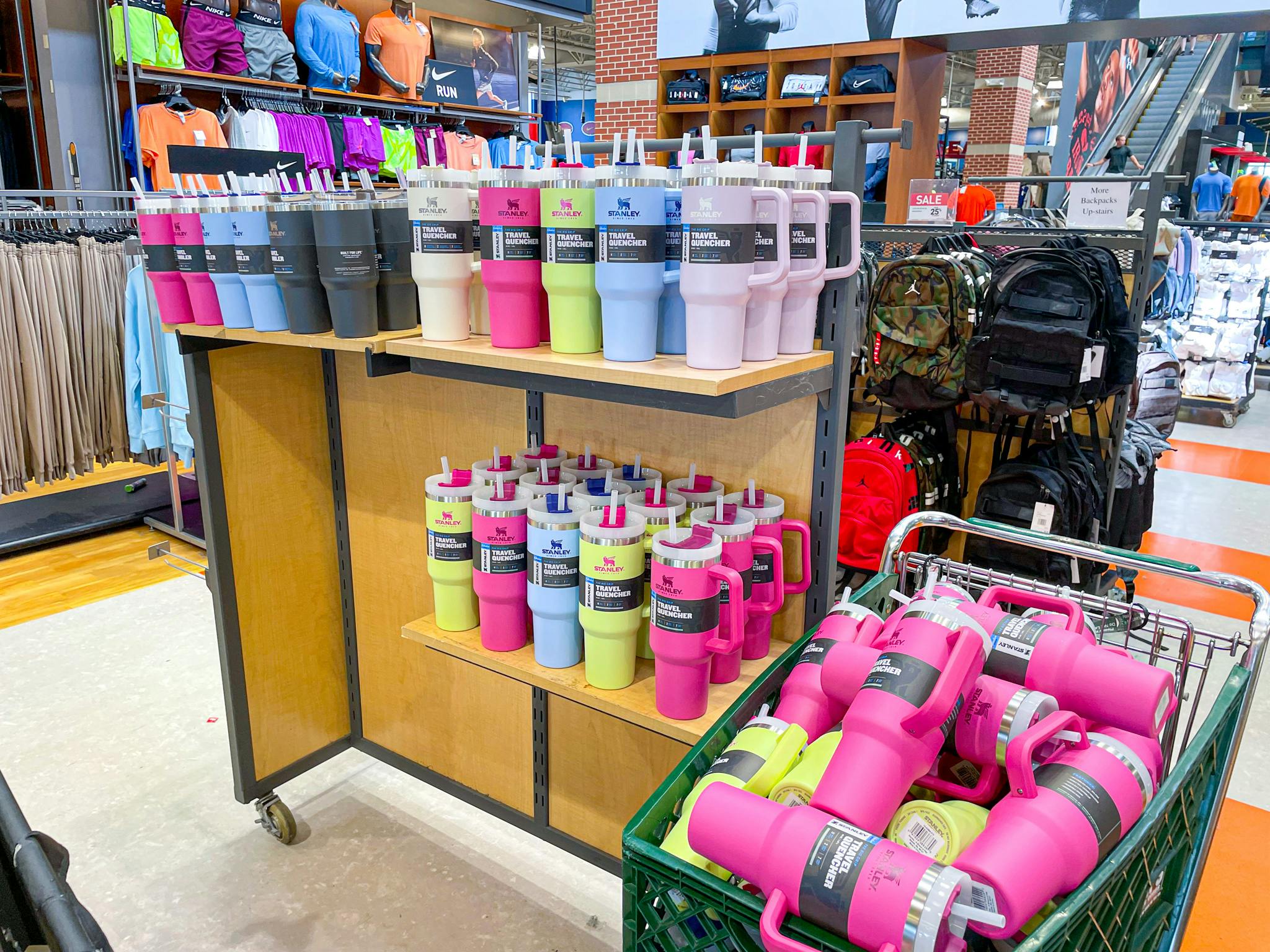 Stanley tumblers in stock at Dick's Sporting Goods on a shelf and in a shopping cart.