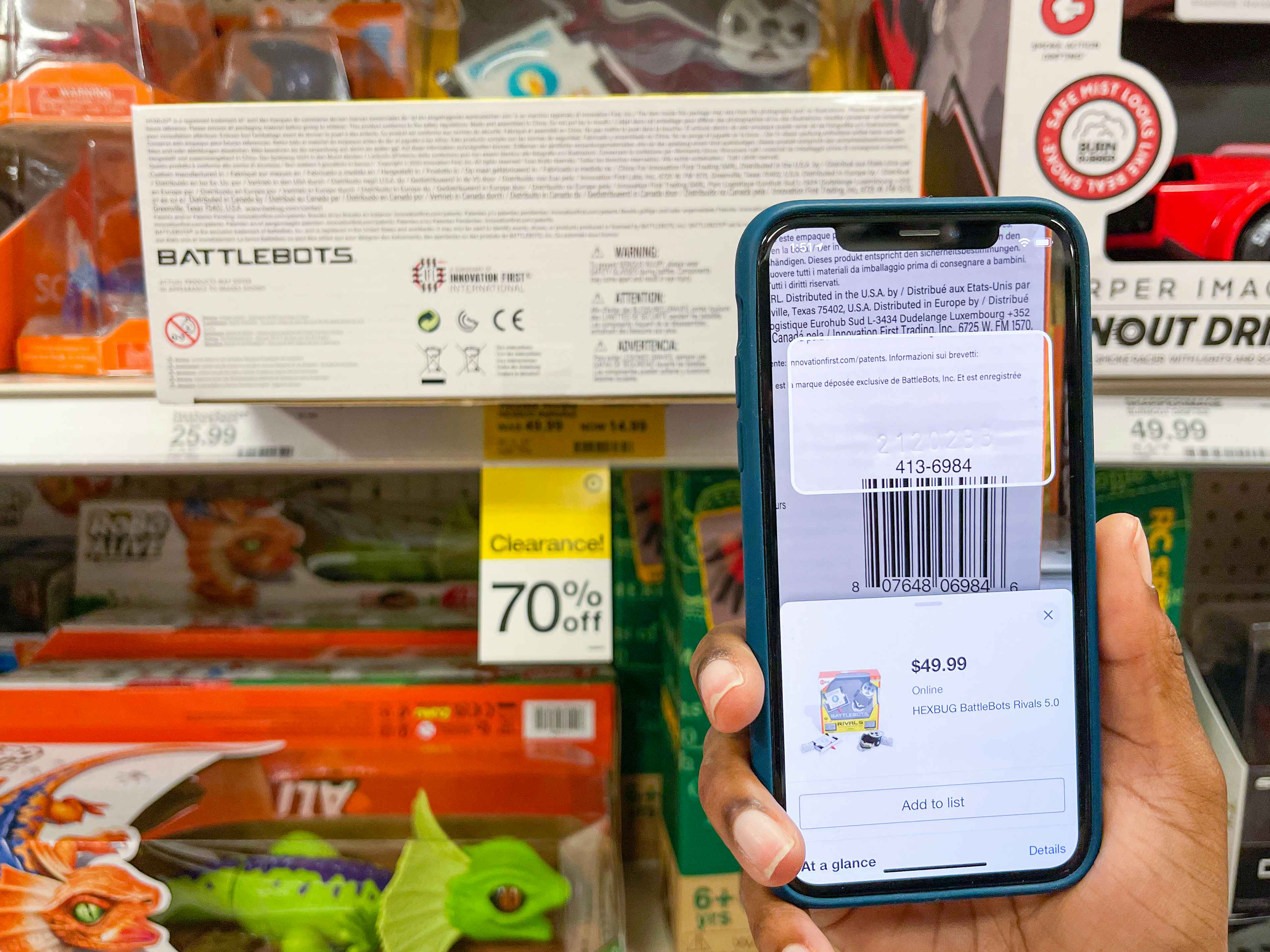 A person's hand holding up an iPhone and scanning a clearance toy's barcode with the Target app.