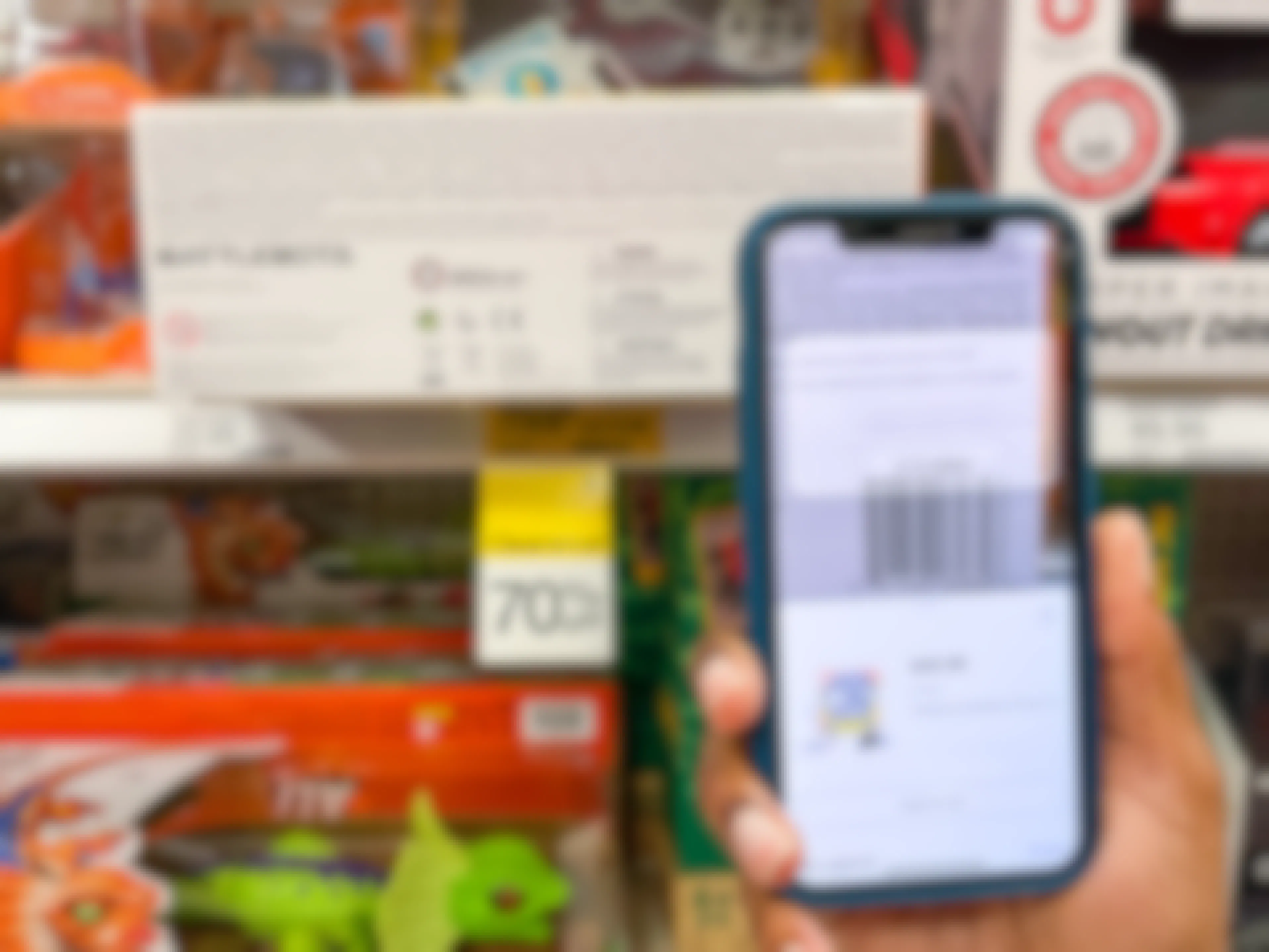 A person's hand holding up an iPhone and scanning a clearance toy's barcode with the Target app.