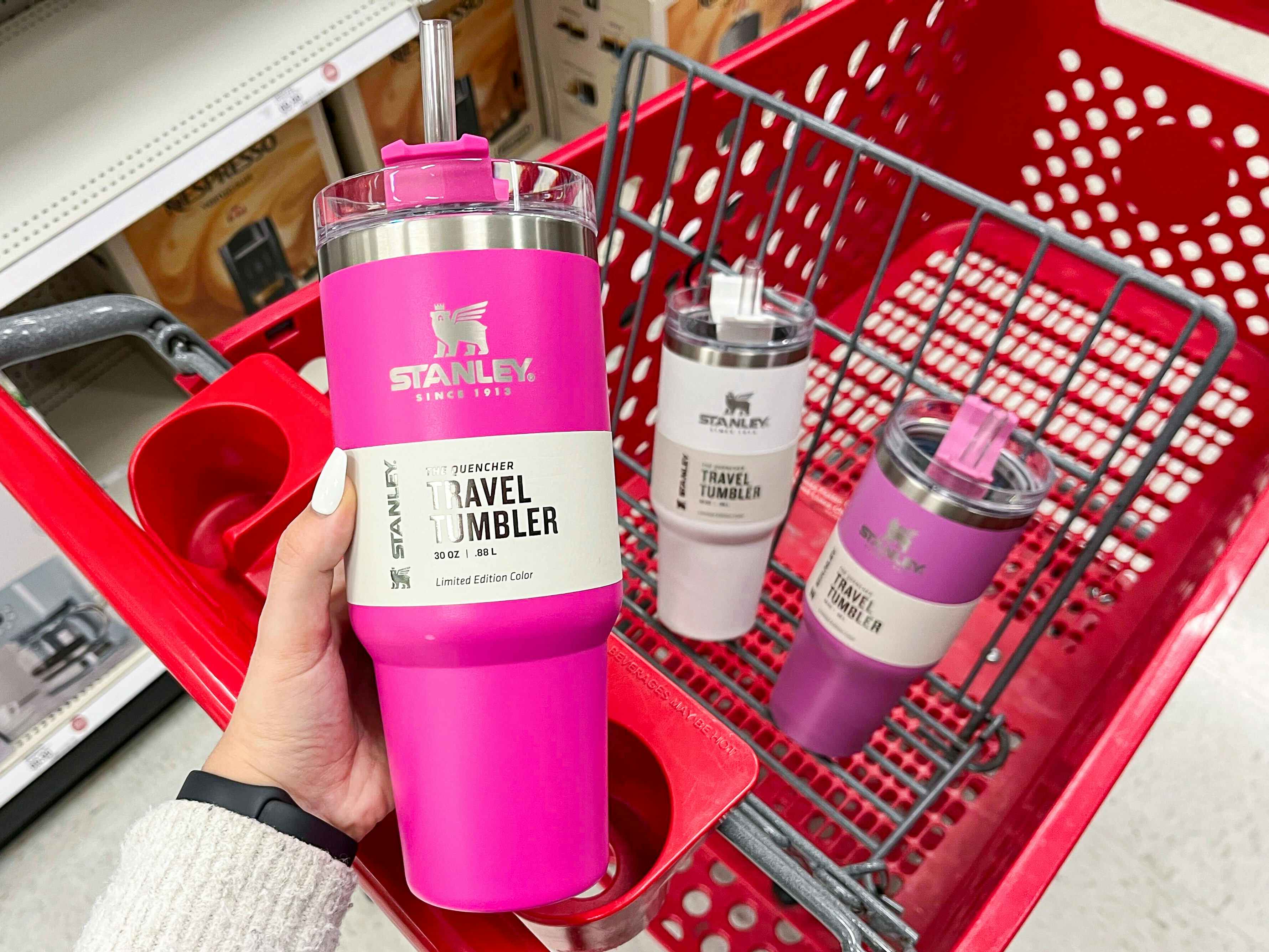 Someone putting a Stanley tumbler into a Target cart