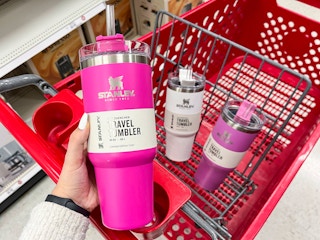 Someone putting a Stanley tumbler into a Target cart