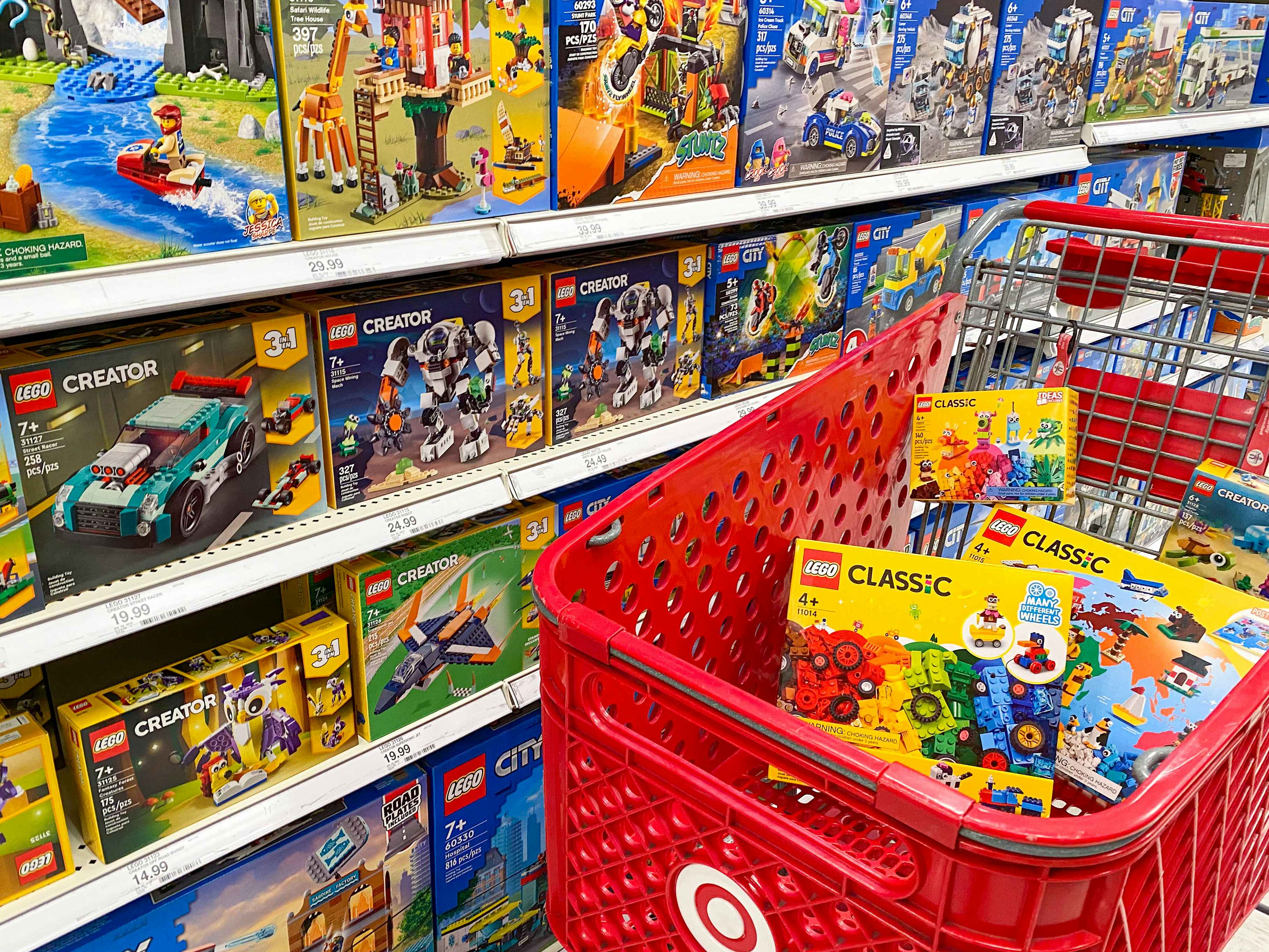 A Target shopping cart full of LEGO toys parked next to a shelf stocked with LEGO toys at Target.