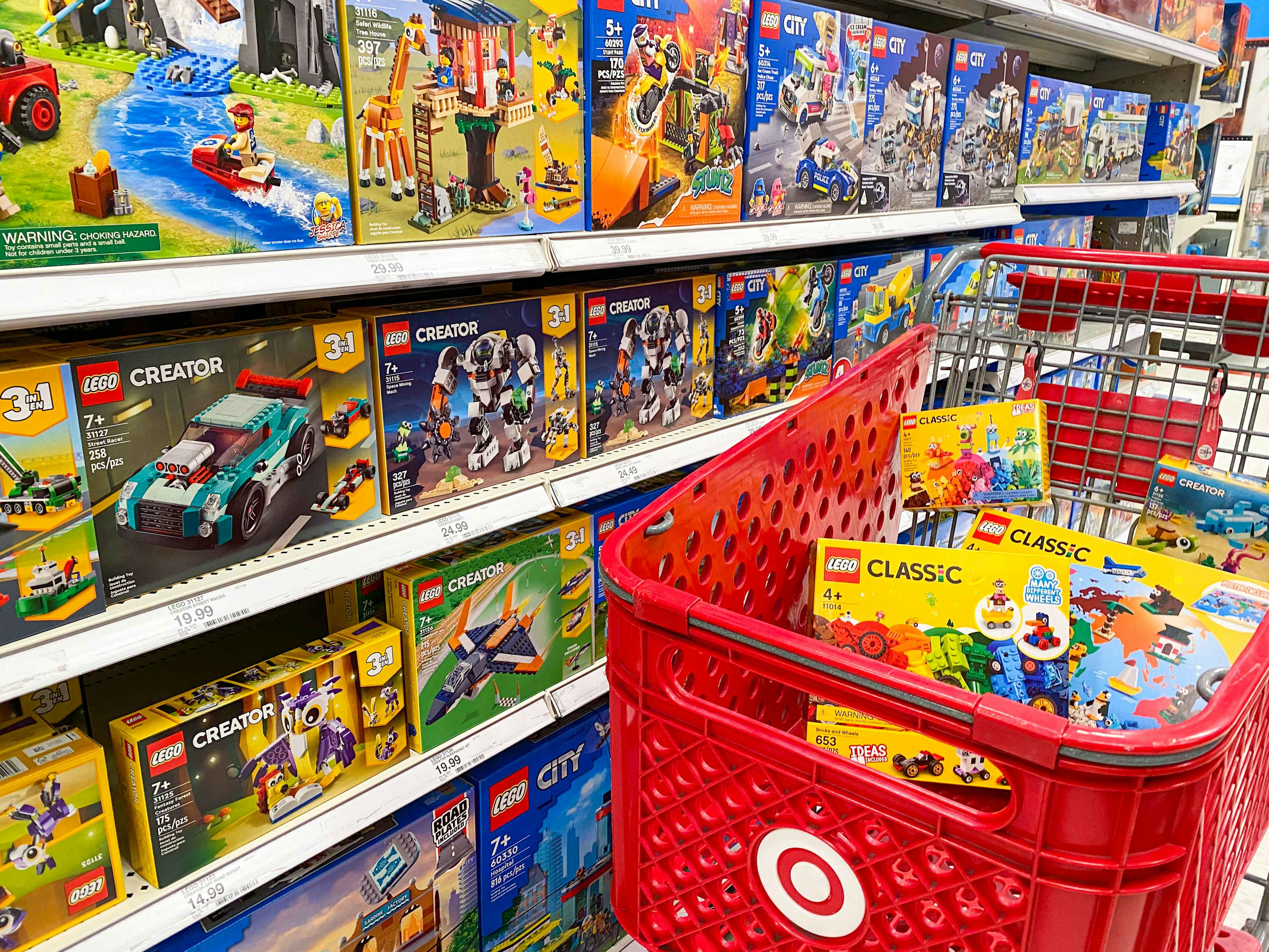 A Target shopping cart full of LEGO toys parked next to a shelf stocked with LEGO toys at Target.