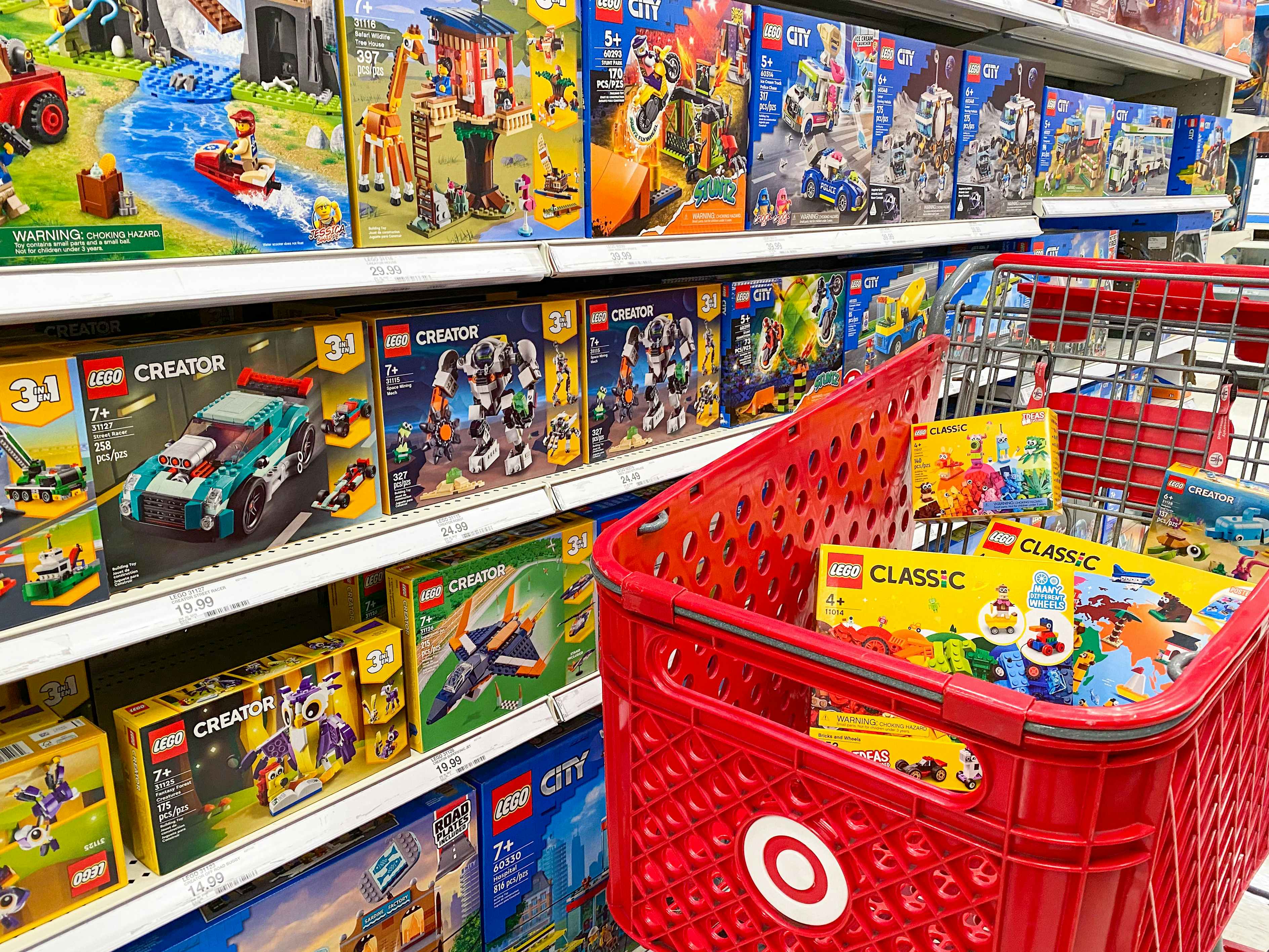 A Target shopping cart full of LEGO toys parked next to a shelf stocked with LEGO toys at Target.