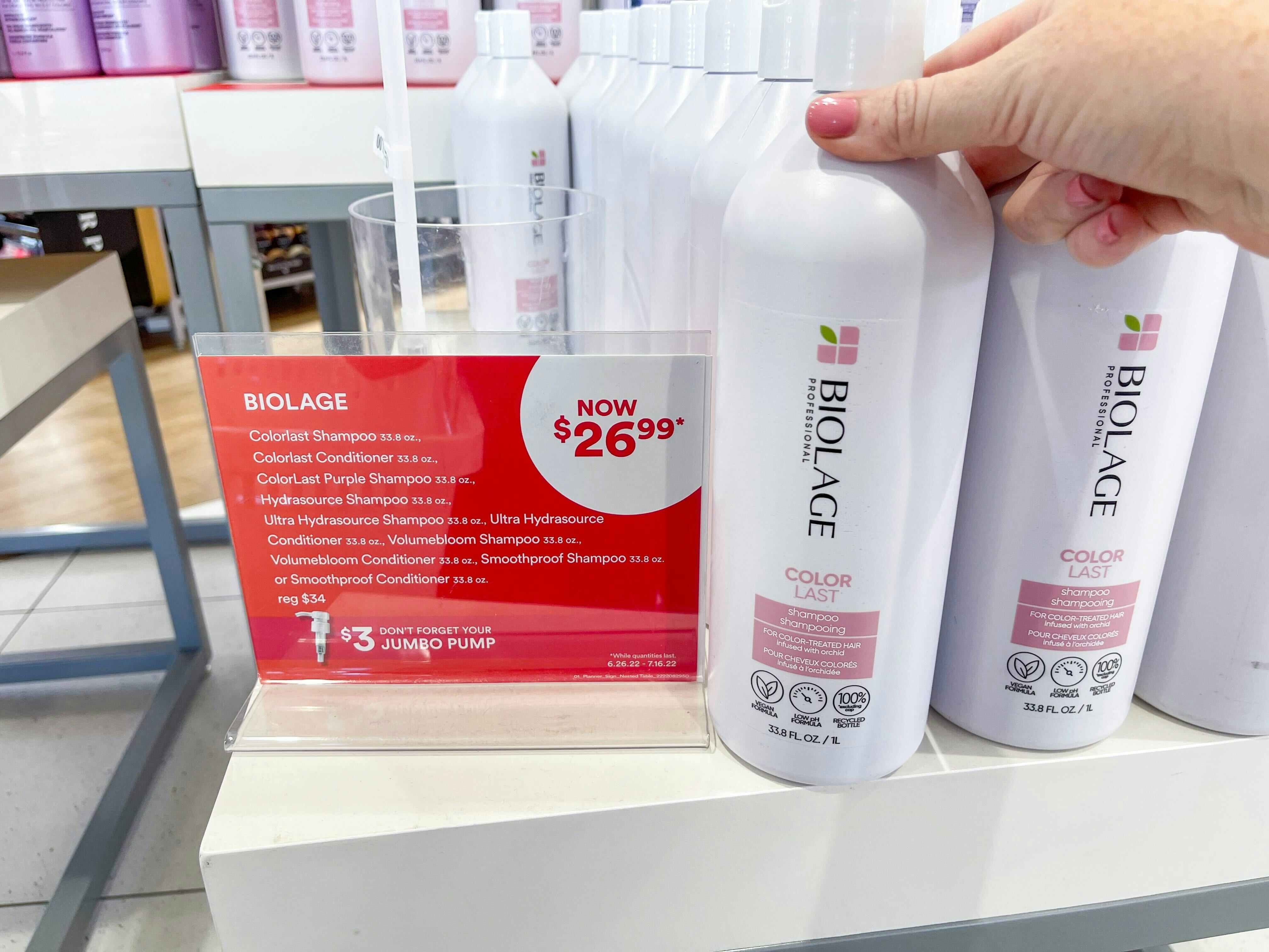 someone holding a jumbo biolage hair product by a sign saying the sale price