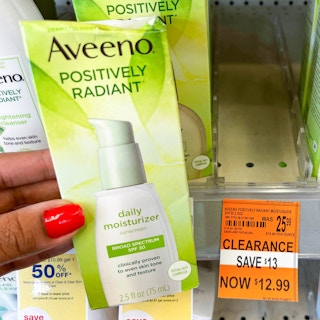 hand holding up box of Aveeno Positively Radiant daily moisturizer next to clearance tag