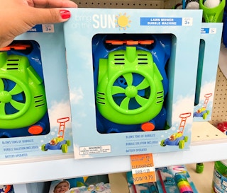 hand touching box with Lawn mower bubble machine on shelf and clearance tag underneath