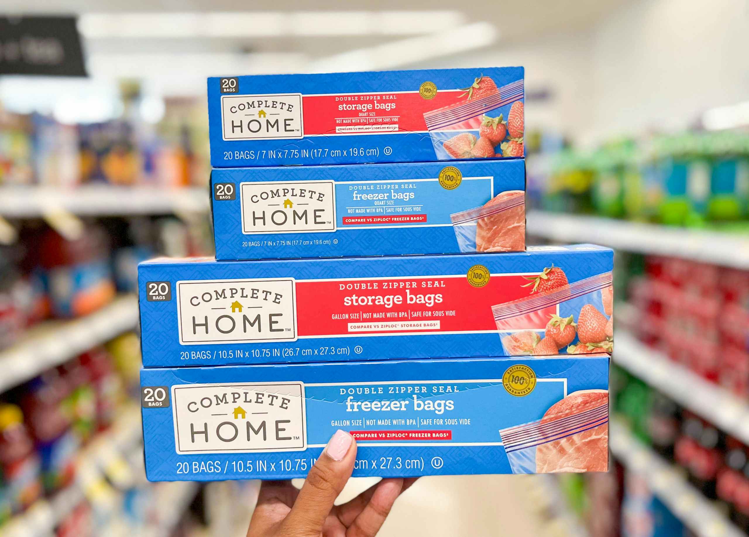 Hand holding a stack of four boxes of Complete Home storage bag boxes