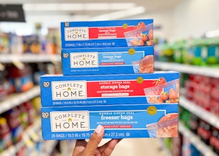 Hand holding a stack of four boxes of Complete Home storage bag boxes