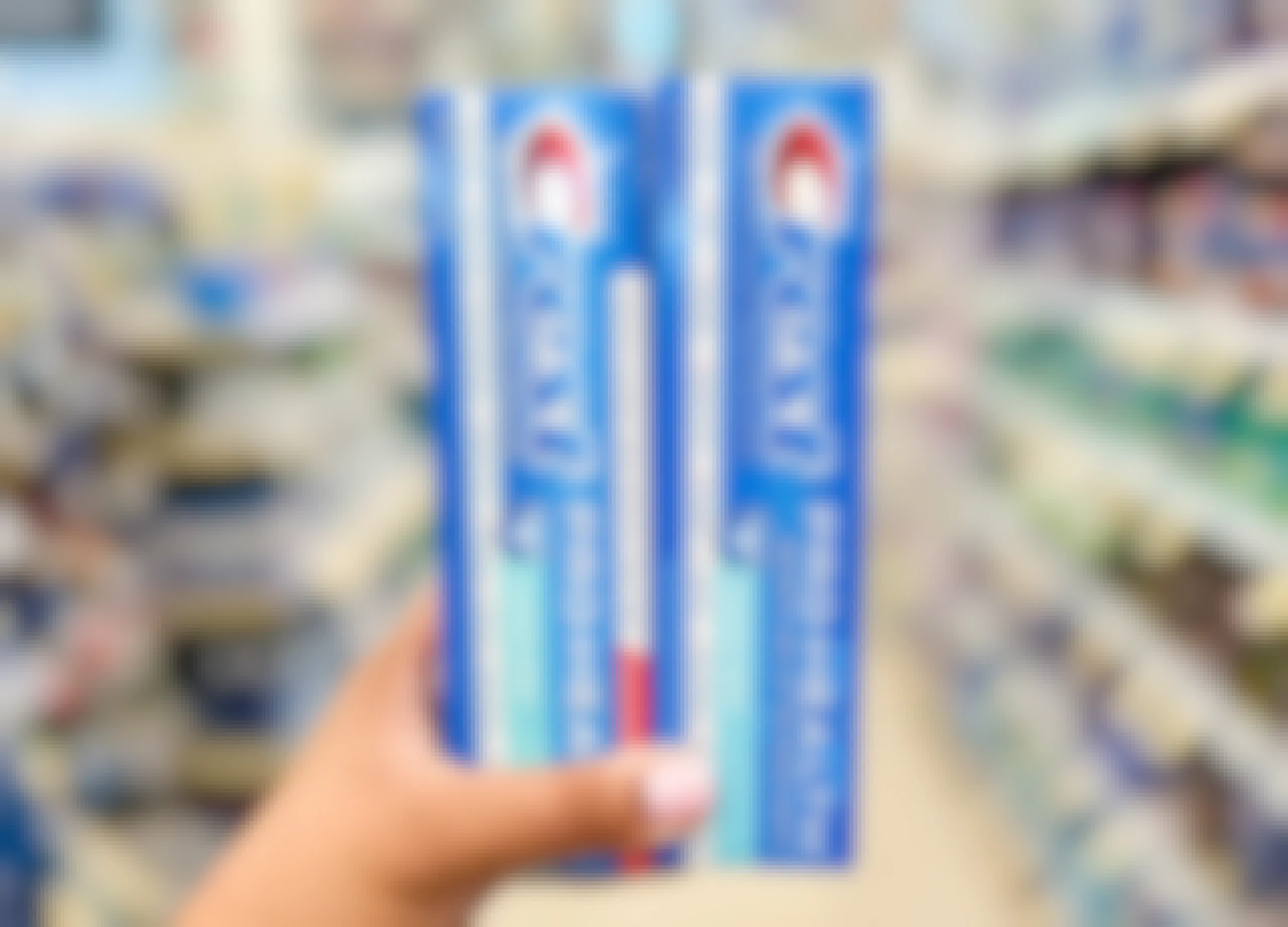 Hand holding two boxes of Crest Pro-Health toothpaste