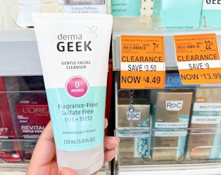 hand holding bottle of DermaGeek facial cleanser next to clearance tag
