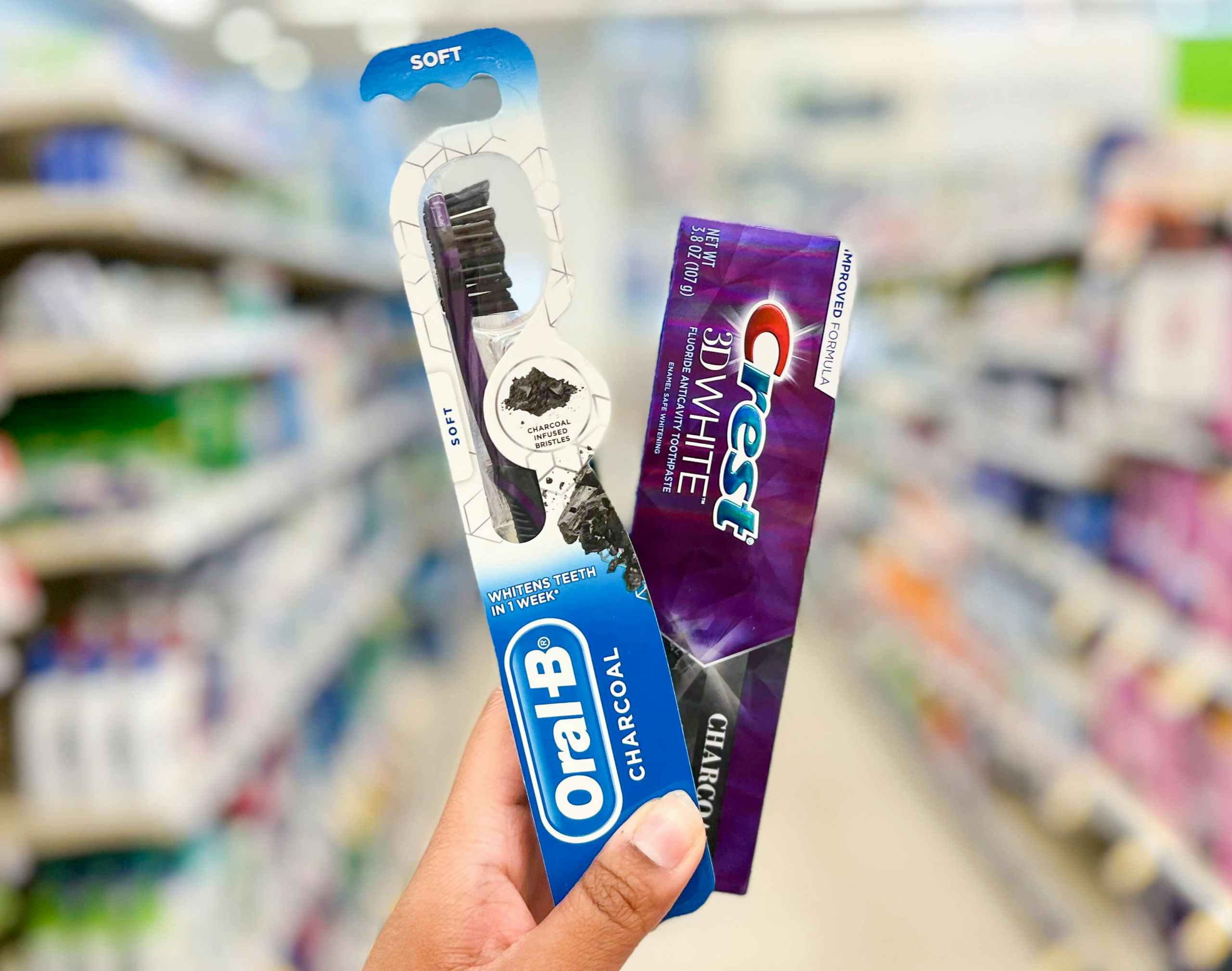 hand holding Oral-B charcoal toothbrush and Crest charcoal toothpaste in aisle