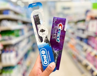 hand holding Oral-B charcoal toothbrush and Crest charcoal toothpaste in aisle