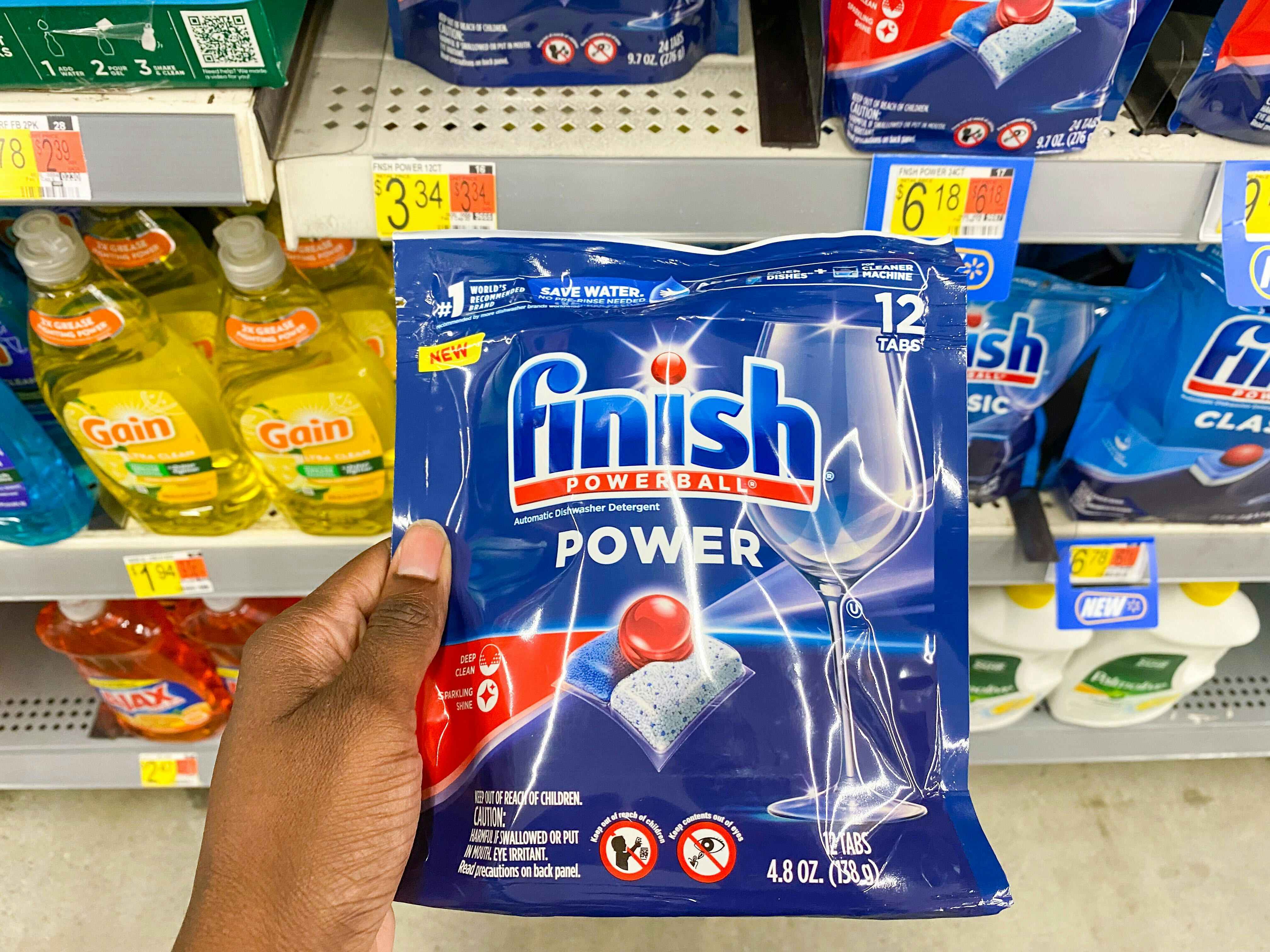Hand holding a 12-count bag of Finish Power Dishwashing Tabs at Walmart
