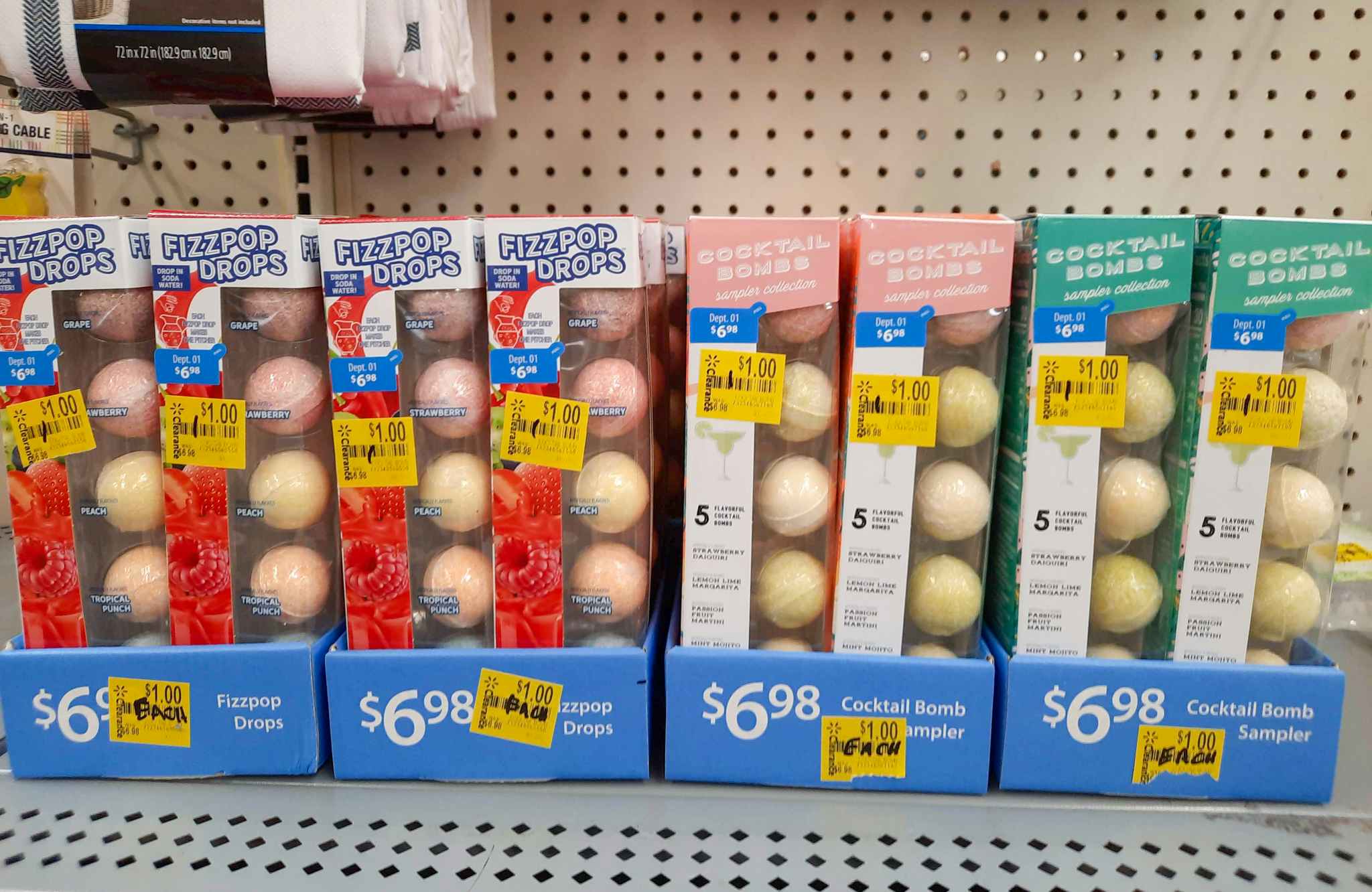 Cocktail Bomb and Fizzpop Drop products on display at Walmart. Each item has a $1 clearance tag attached to the box.