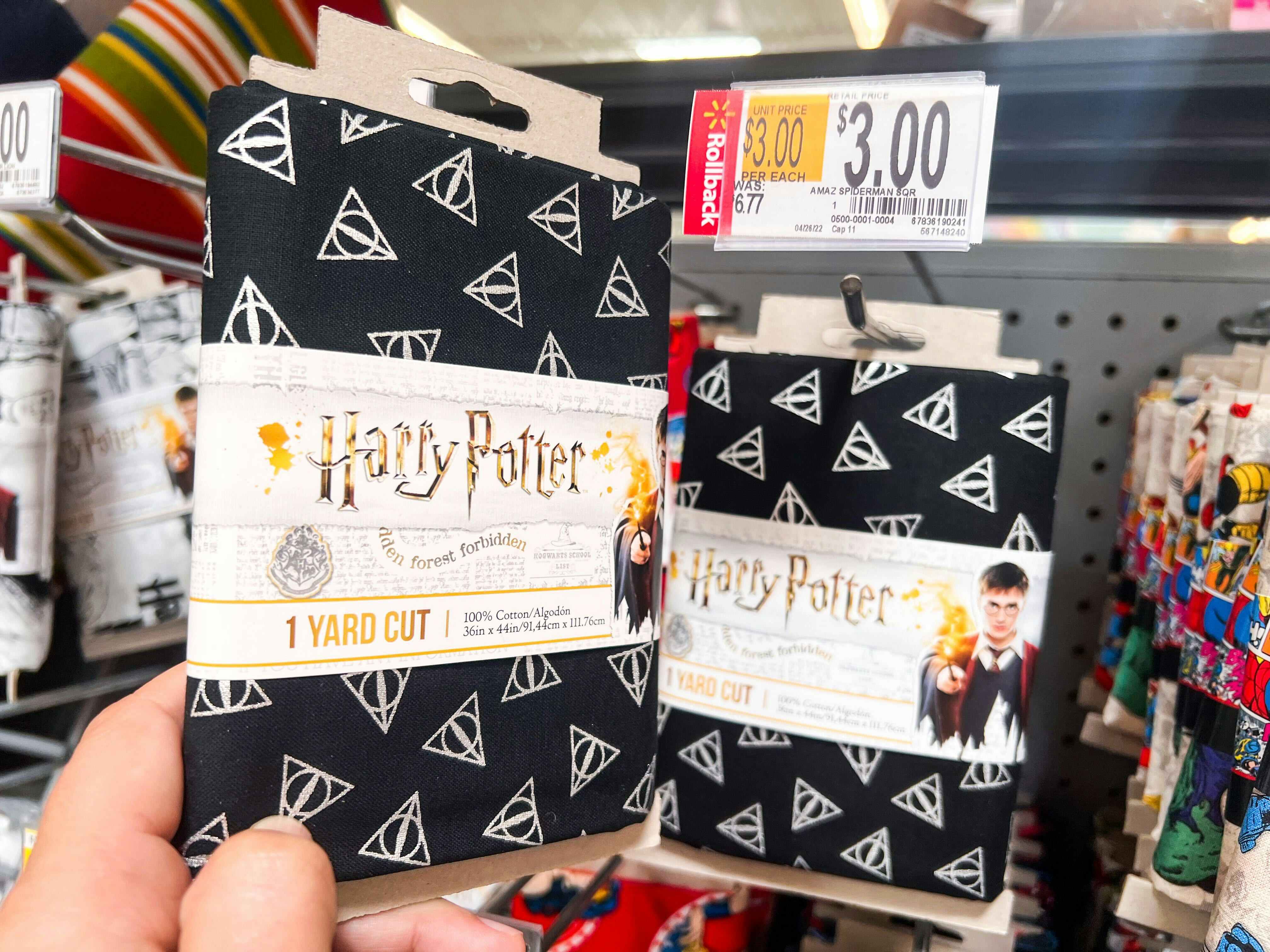 Hand holding Harry Potter printed quilting fabric in front of shelf at Walmart. Price tag indicates that the product is on sale for $3, regularly $6.77.