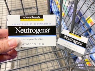 hand holding neutrogena facial cleansing bar over cart at walmart