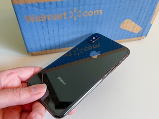 Person holding an iPhone next to a Walmart box.