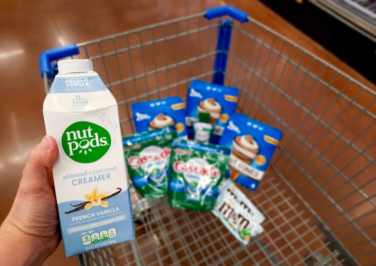 Nutpods Creamer held over Walmart shopping cart full of Blue Bunny, Cascade, and M&M's products