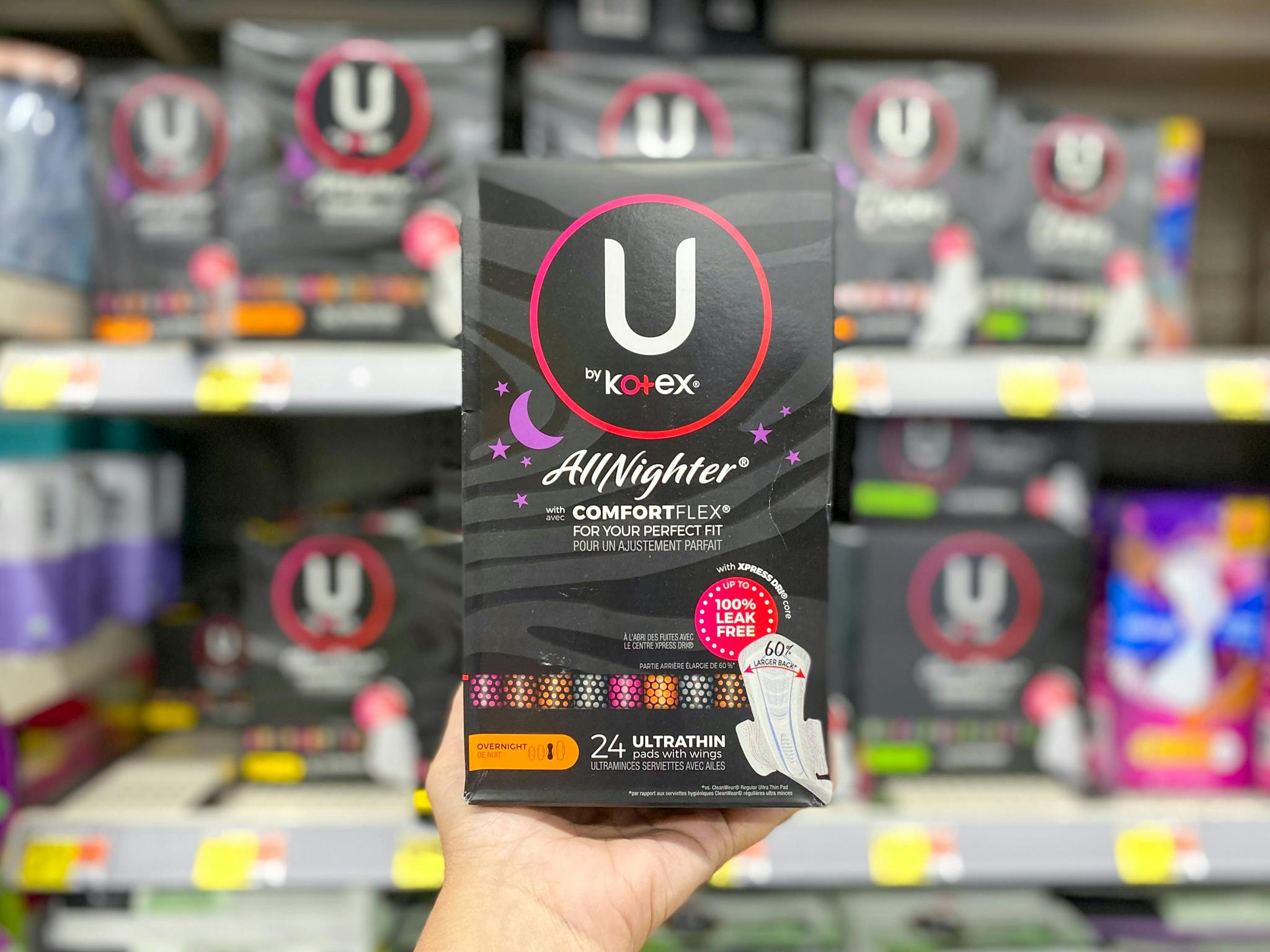 Hand holding a box of U by Kotex AllNighter Pads at Walmart