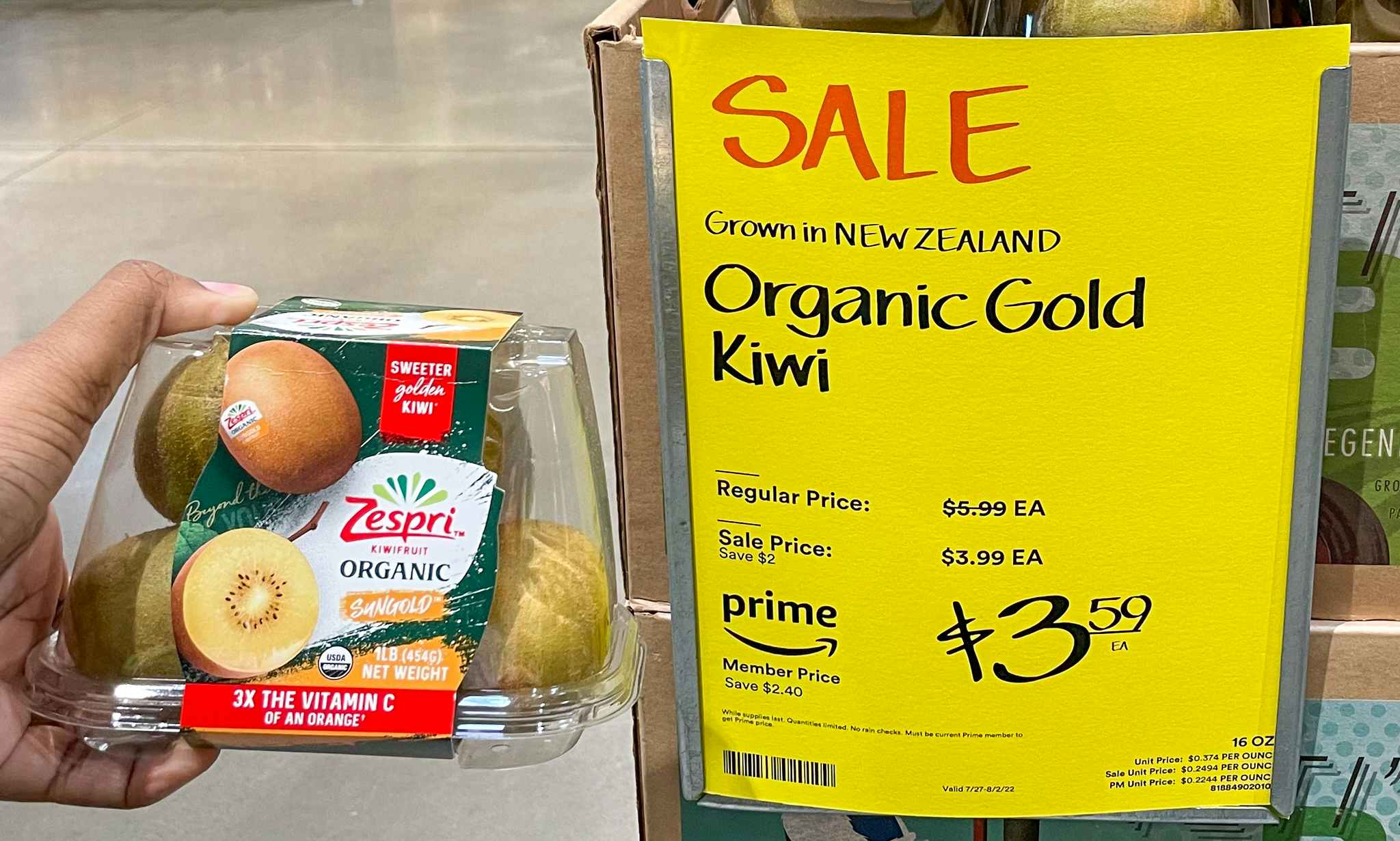 packaged kiwi hand held near sales sign at whole foods