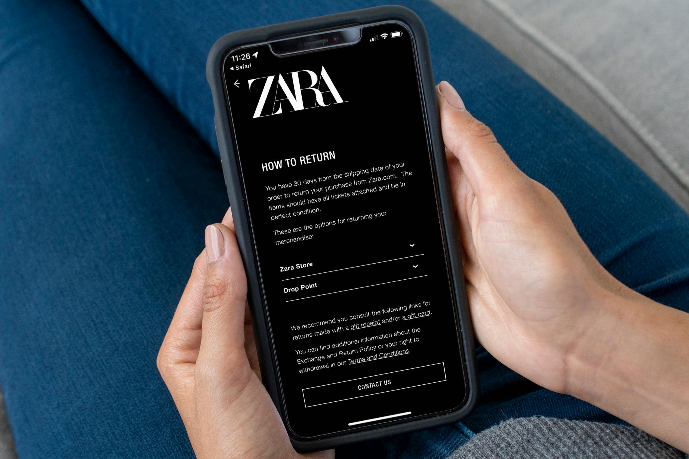 A person holding an iPhone displaying the Zara return policy on their website.