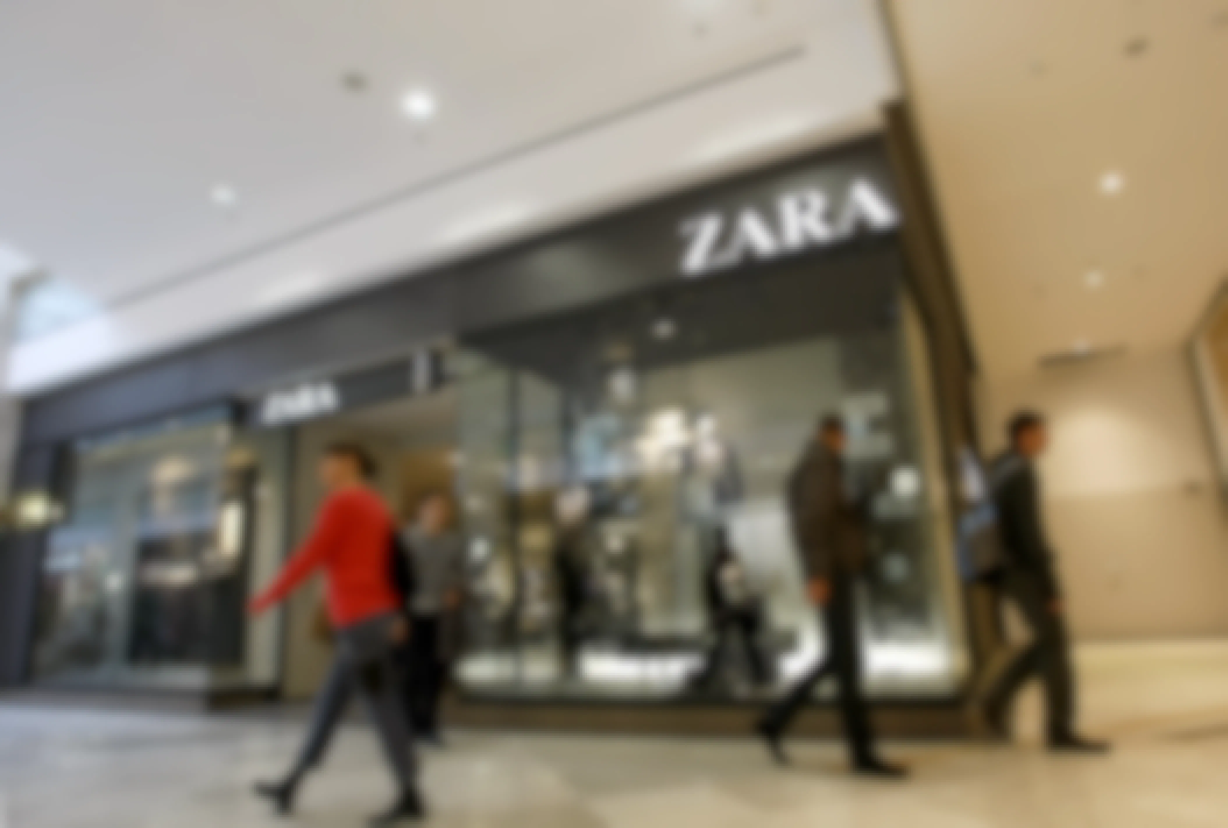 A Zara store inside a mall with shoppers passing by.