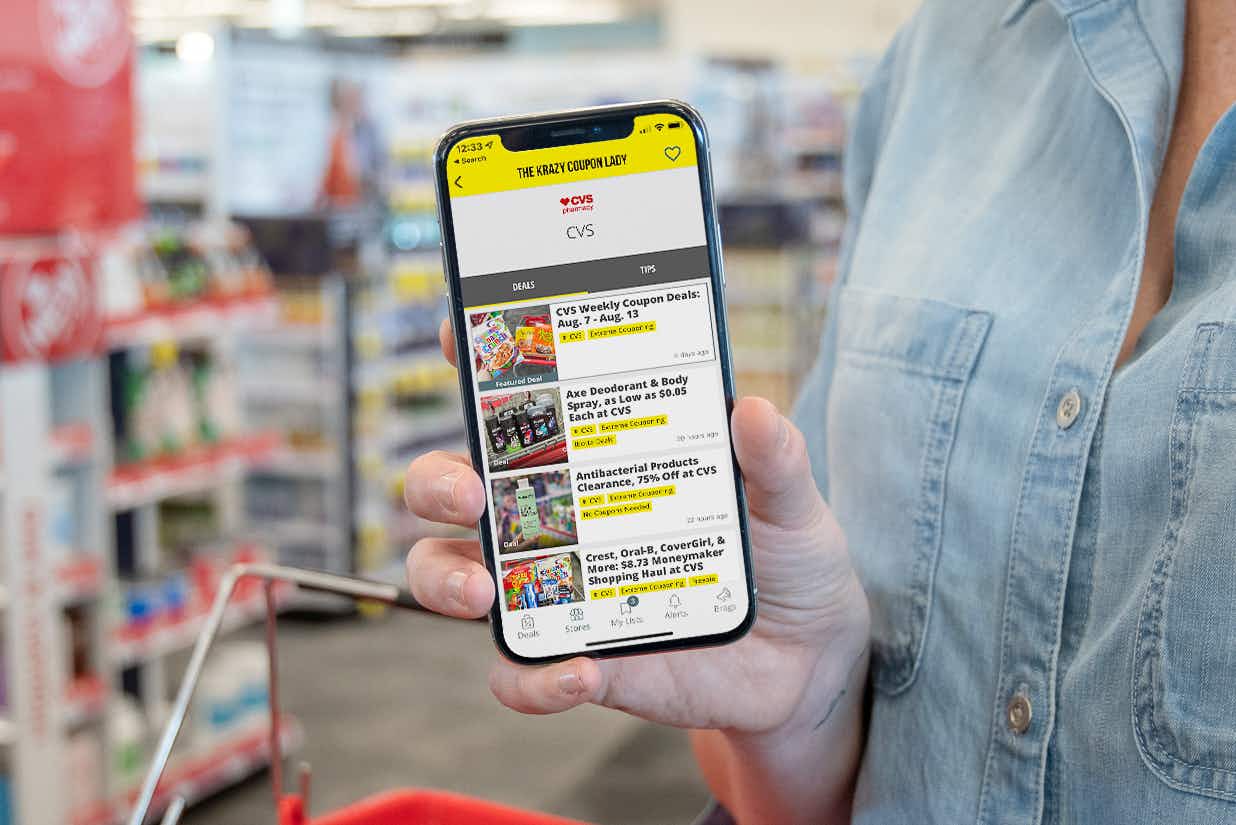 A woman holding up an iPhone displaying the CVS deal page on the KCL app.