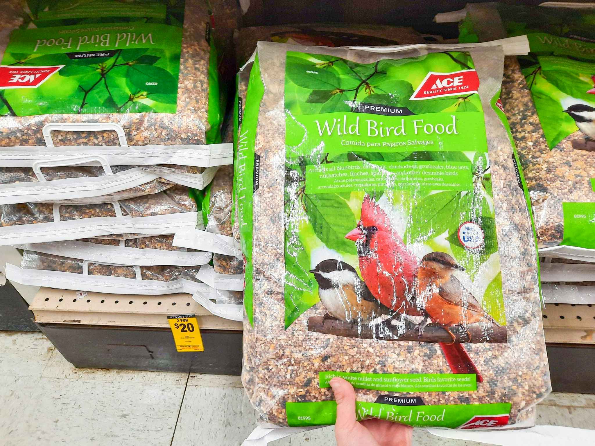 Hand grabbing a 20-pound bag of Ace Hardware brand Wild Bird Food off the shelf.