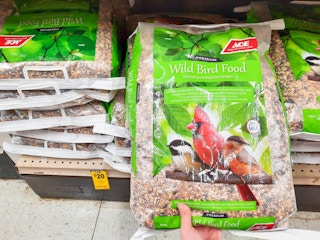 Hand grabbing a 20-pound bag of Ace Hardware brand Wild Bird Food off the shelf.