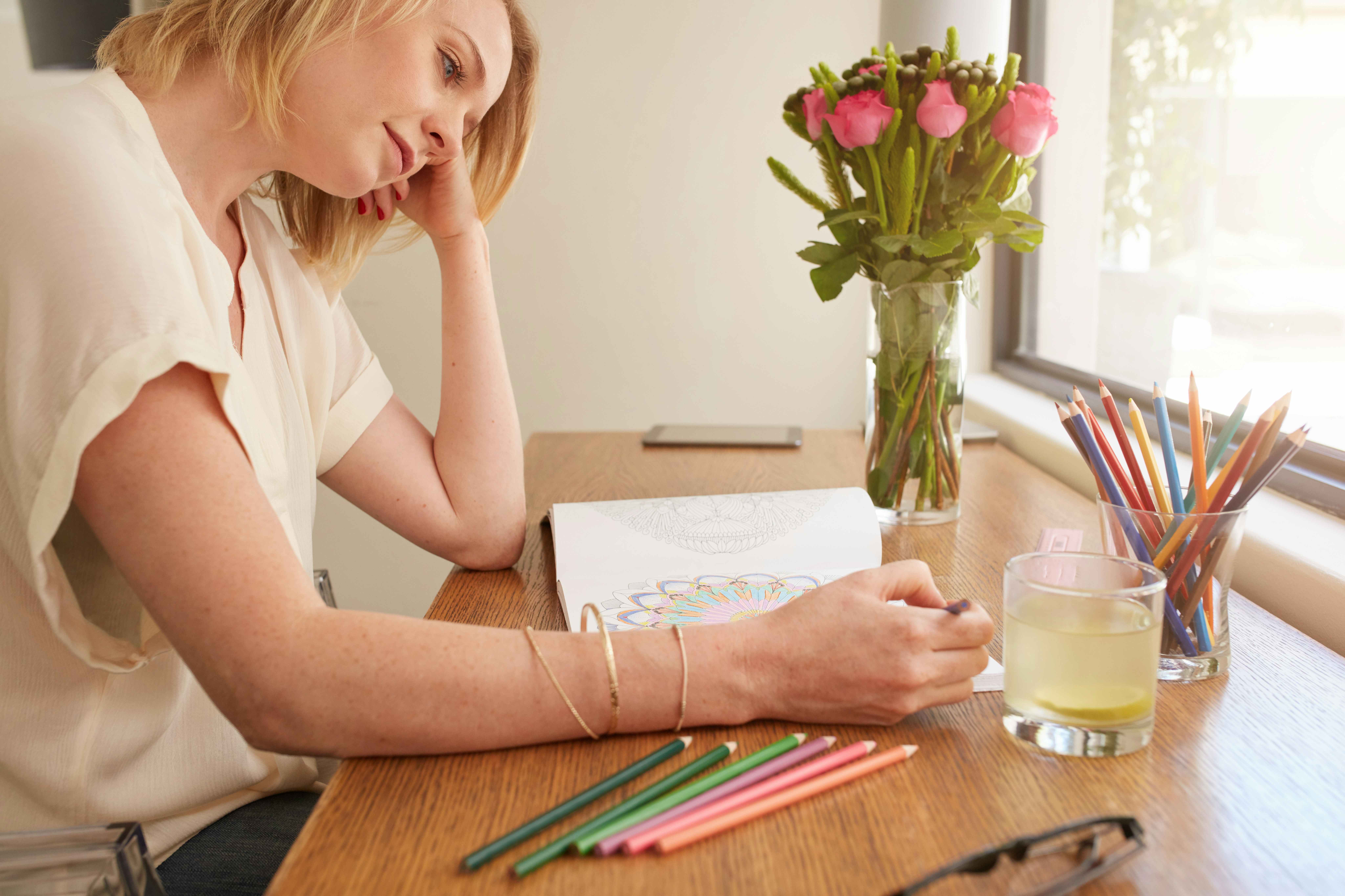 A person using colored pencils to color in an adult coloring book.