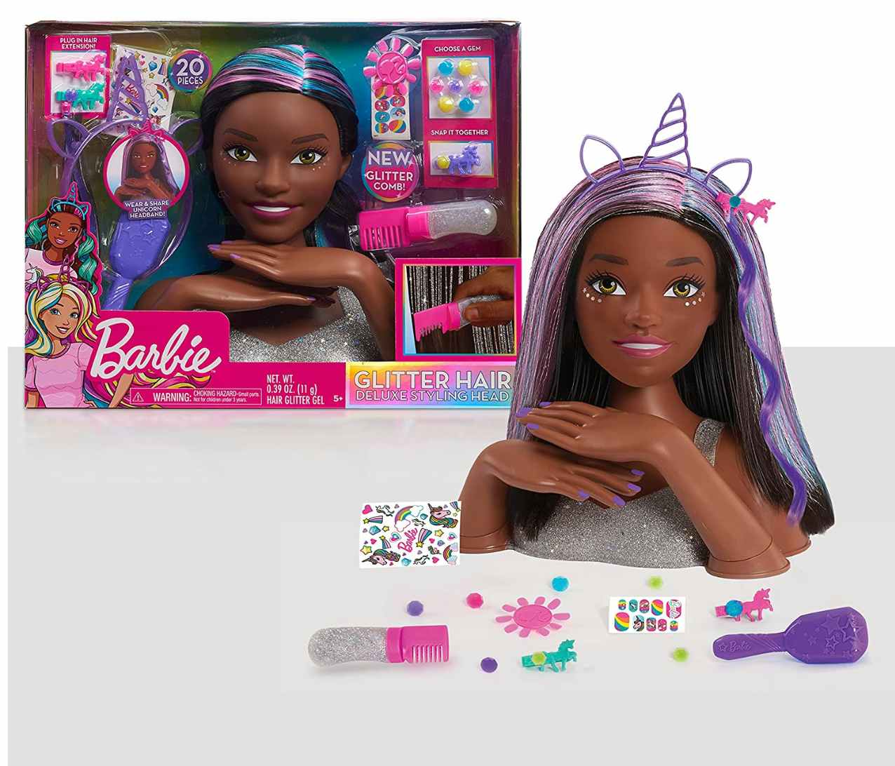 A Barbie styling head on a table with the accessories and packaging