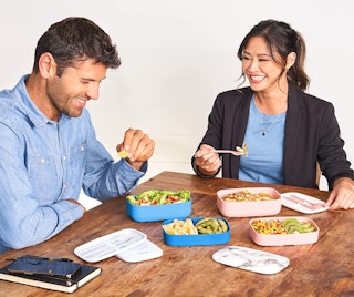 Two people having lunch at a table with bento box containers