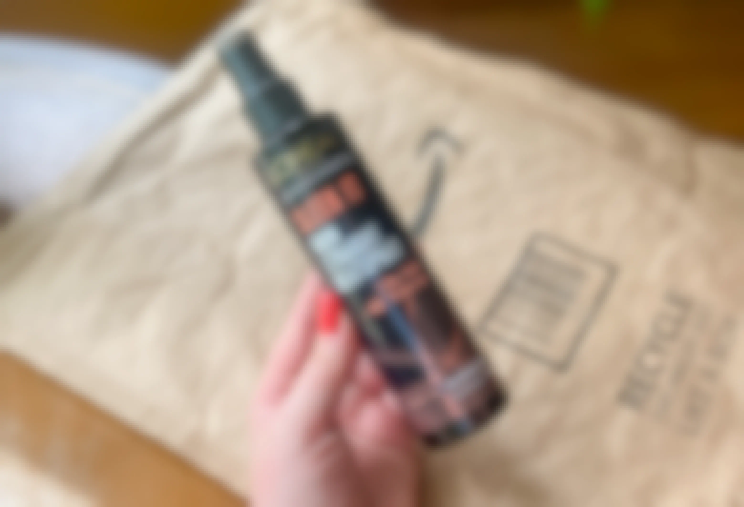 hand holding l'oreal sleek it heat protectant spray in front of an amazon envelope