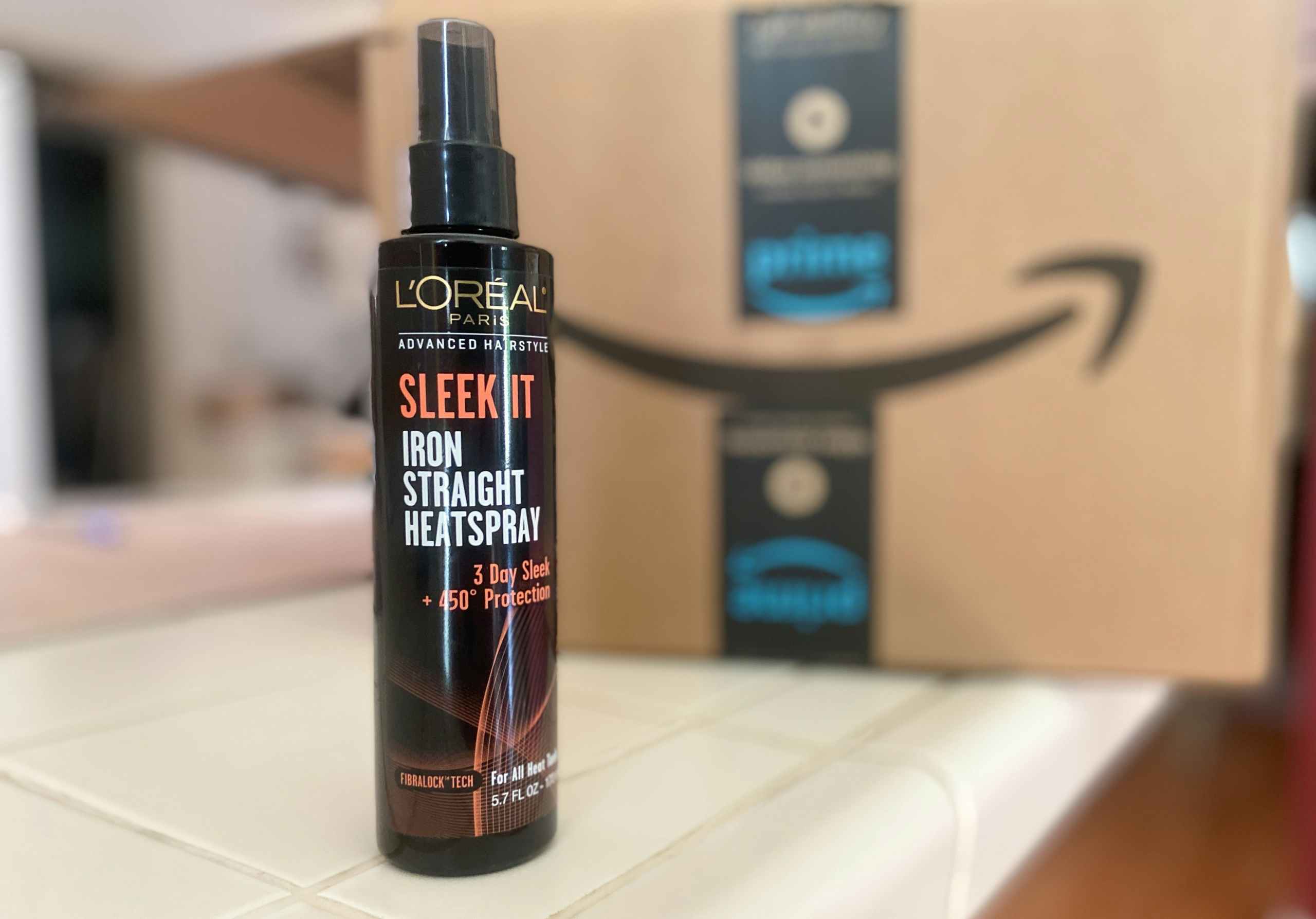 l'oreal sleek it heat protectant spray in front of an amazon box