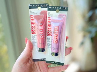 hand holding two maybelline cheek heat cream blush makeup