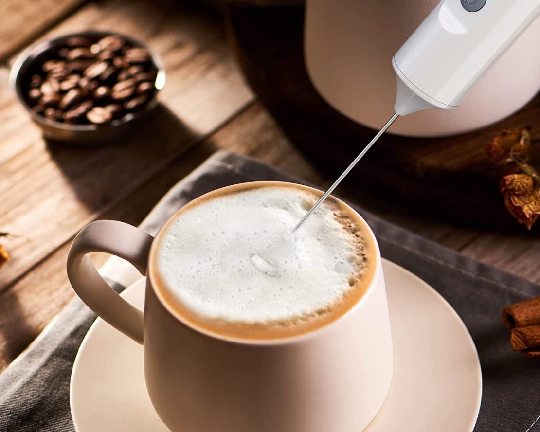 A milk frother in a coffee drink on a table