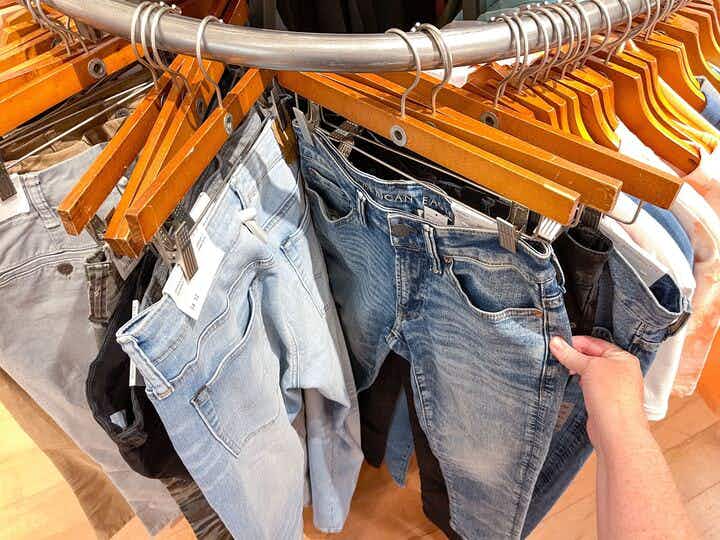 A person looking through jeans on hangers in American Eagle.