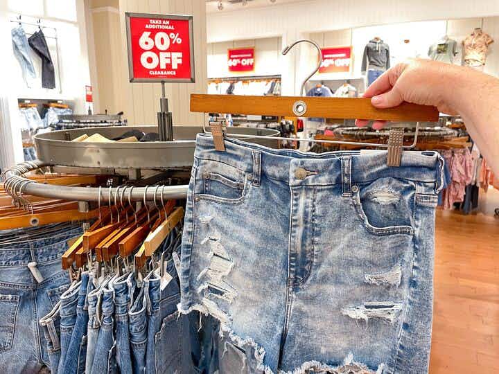 someone holding up denim shorts in the clearance section of American Eagle
